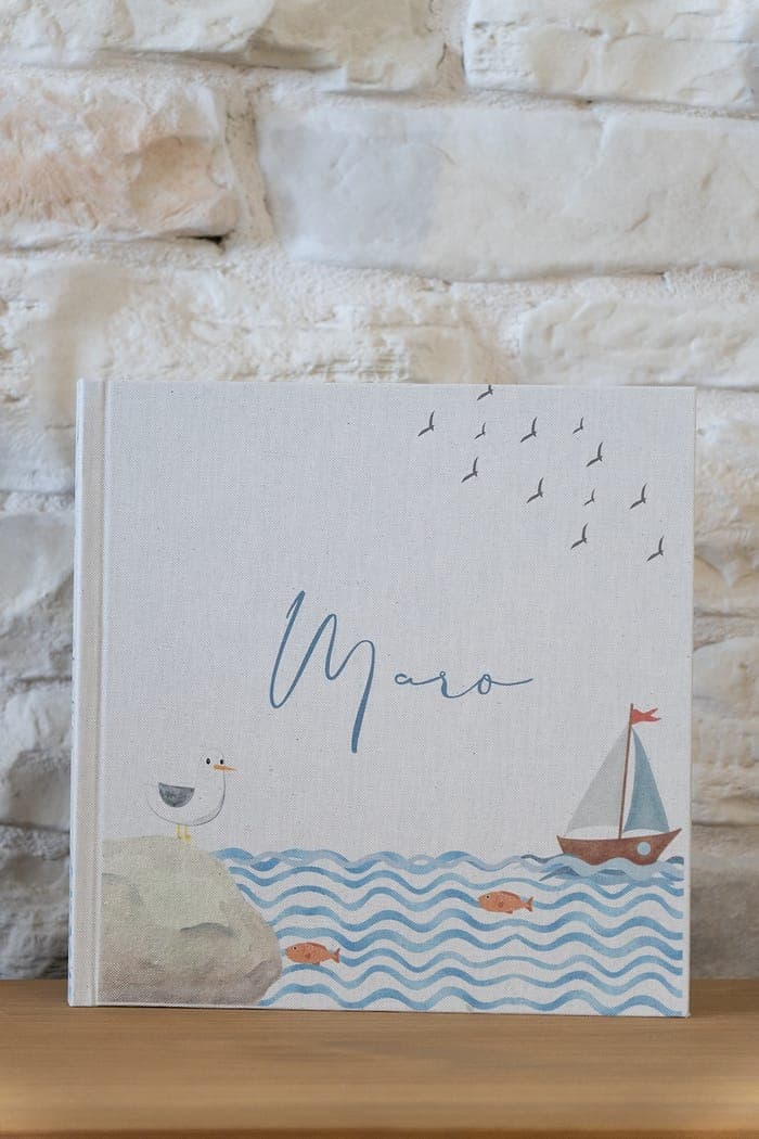 Sea cover, an illustrated sailboat on blue watercolour waves.